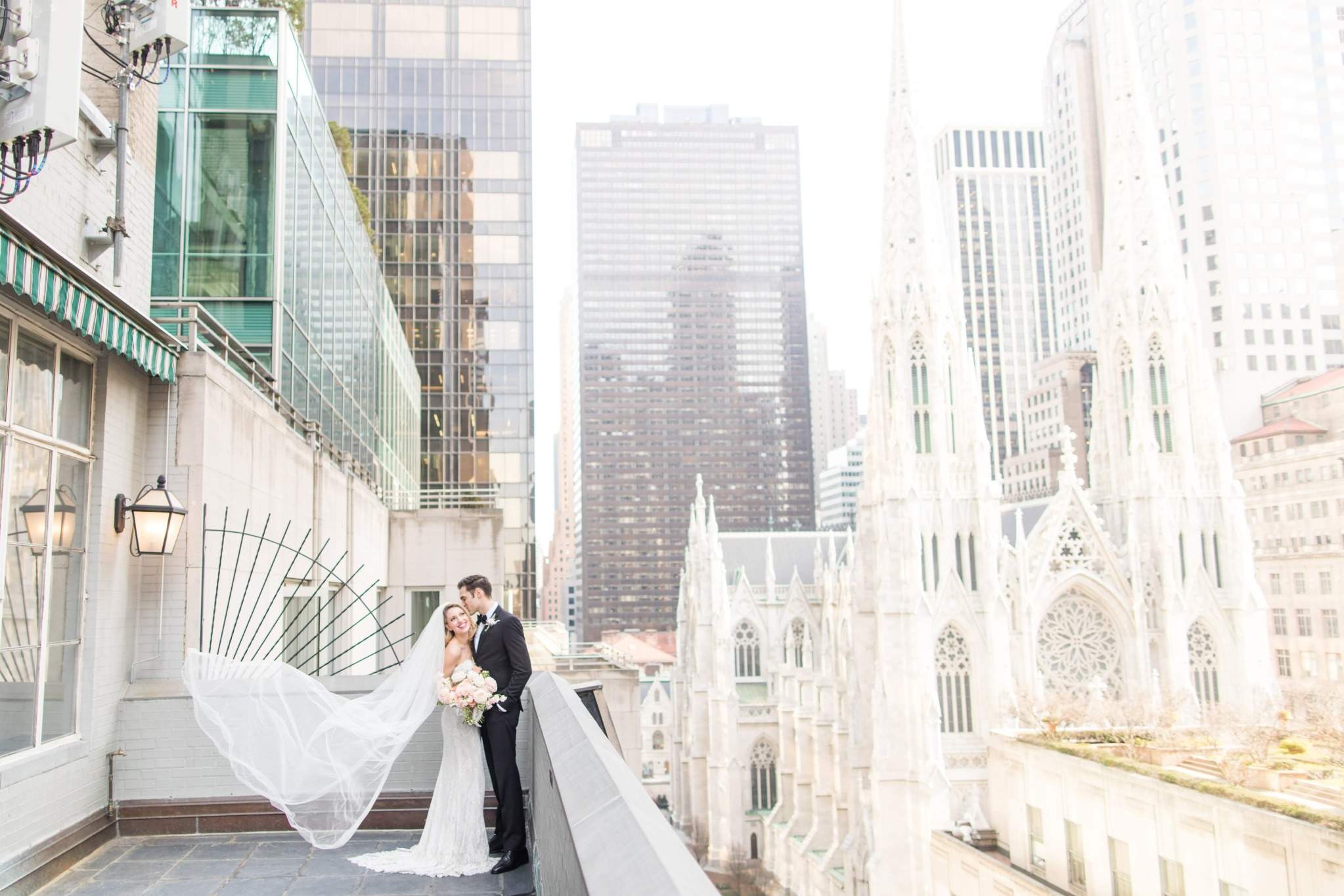 Bride and groom on New York rooftop terrace with cathedral backdrop