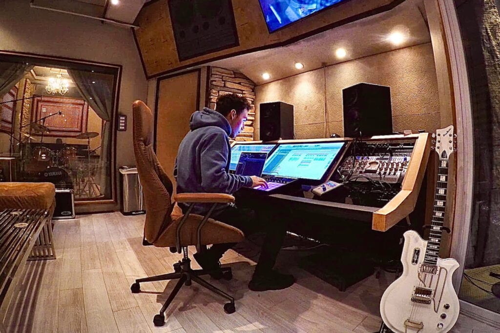 A man sits at a mixing table at a recording studio