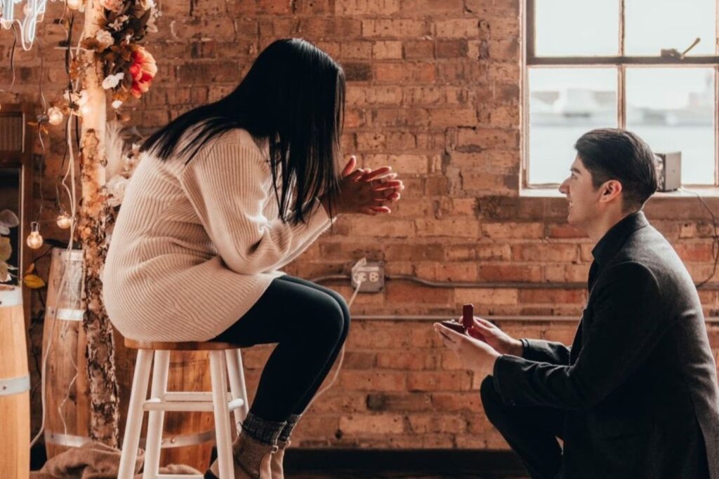 a man proposing to a woman in a rustic brick wall venue
