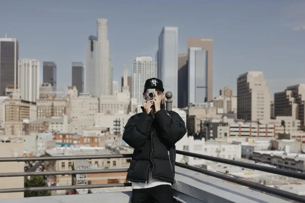 A man takes a photo with a cityscape behind him