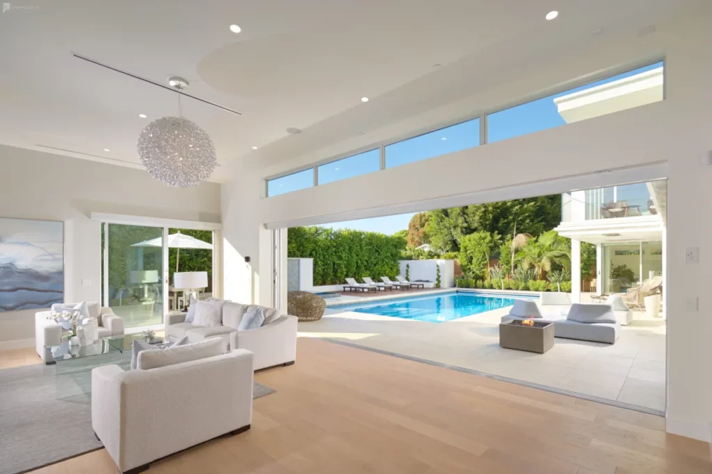 a mansion with a living space that opens to a backyard pool