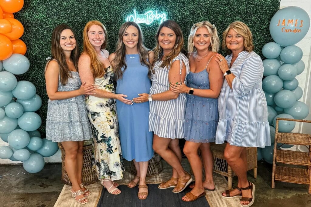 An expectant mother stands with friends and family at her baby event