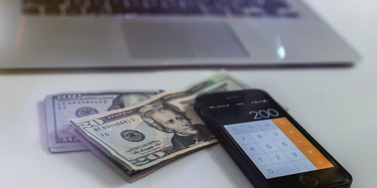 laptop and phone with cash