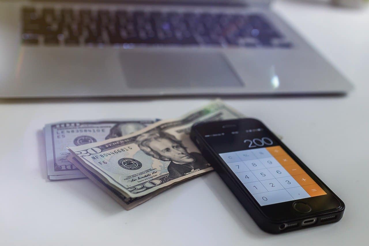 laptop and phone with cash