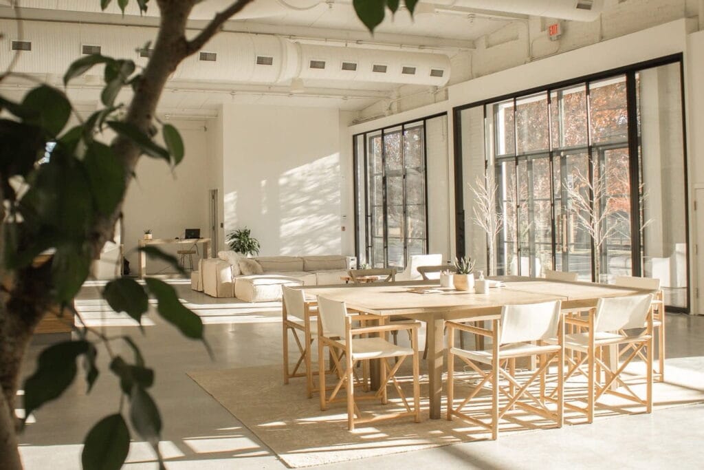 Neutrally-decorated event/party space with floor-to-ceilings windows and doors bringing in tons of sunlight