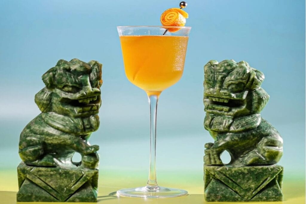 Two green dragon statues stand next to a yellow cocktail