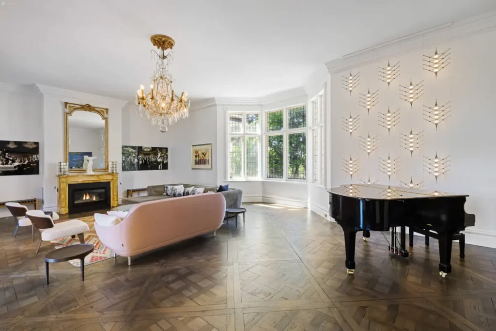 an estate living room with a piano and chandelier