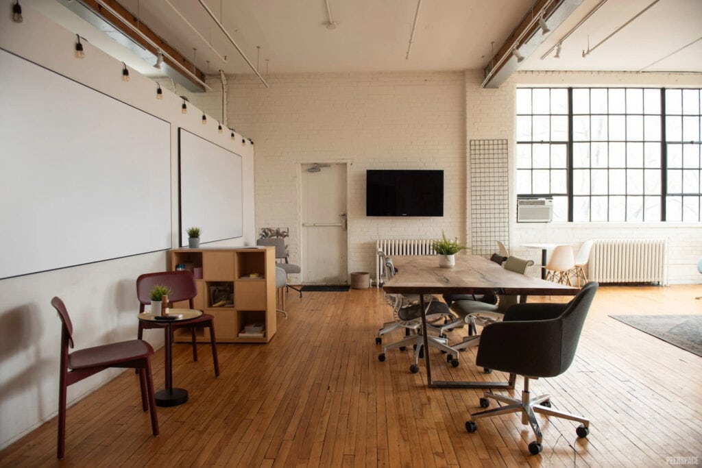 Industrial-style office space with white boards, breakout tables, white brick walls and tall warehouse-like windows