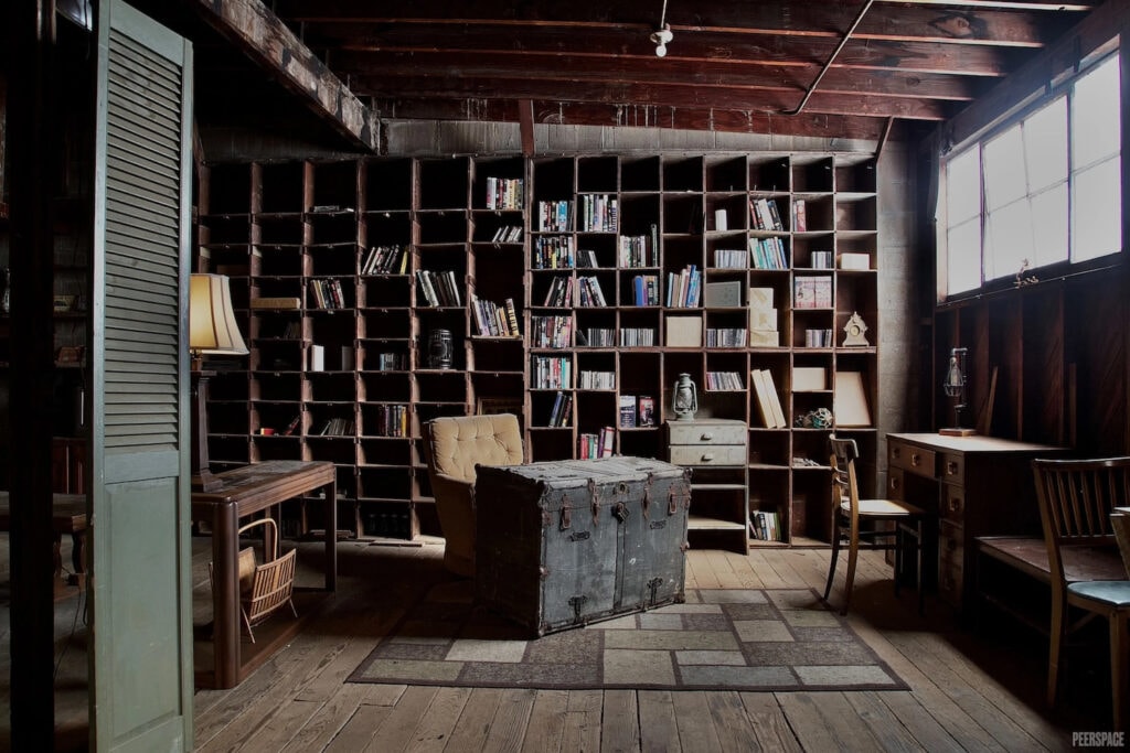 Film set with old bookshelves lining wall, a recliner and a weathered chest