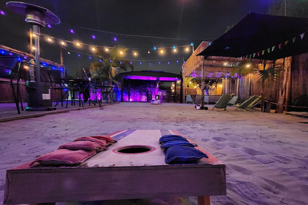 Close up of a corn hole board at an outdoor bar set in the sand in San Diego