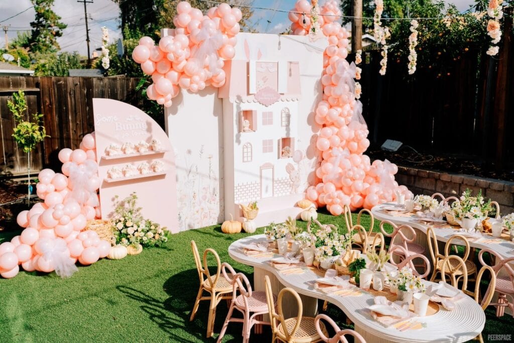 Pink balloons and a pink and white backdrop decorate a baby event celebrating a little girl