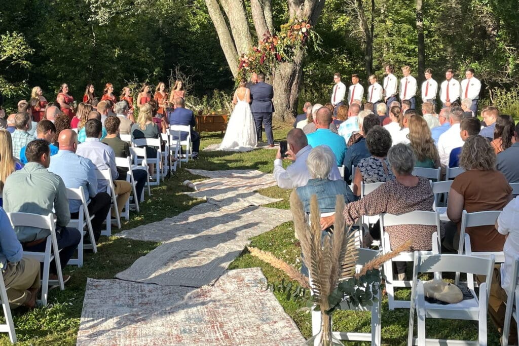 A couple exchanges vows outside in the bright sunshine surrounded by friends and family