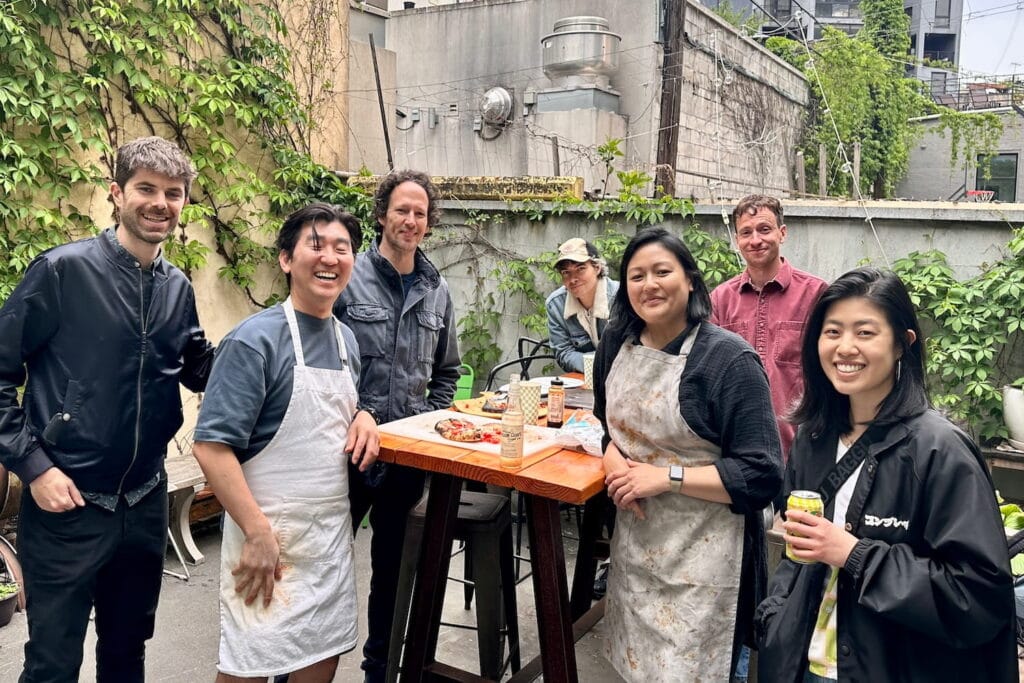 A group of friends pose for a photo around a table on a city rooftop