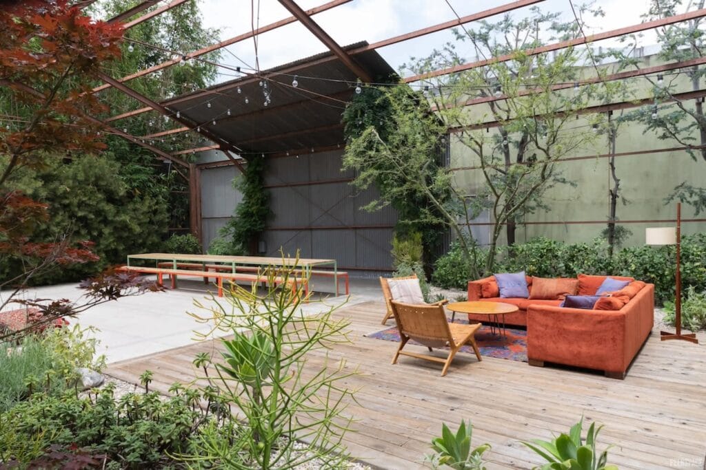 Outdoor garden space with couches and chairs and brightly-colored picnic table