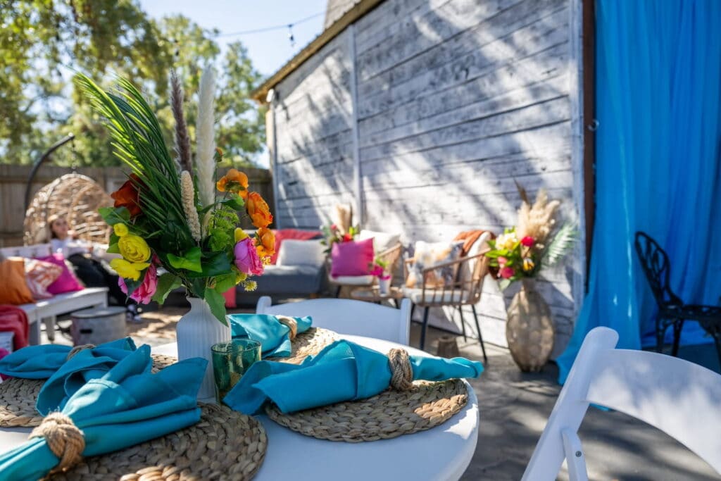 Bright, tropical flowers decorate a Miami backyard set up for a party with turquoise linens and bright sunshine illuminating the space