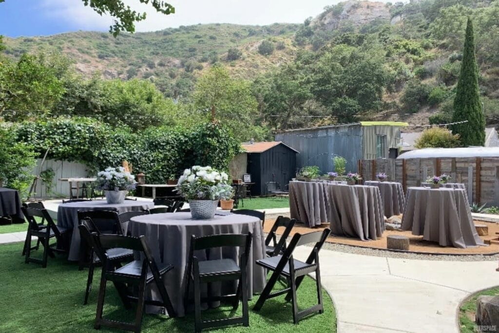 Small outdoor tables are set with large centerpieces for a casual wedding reception