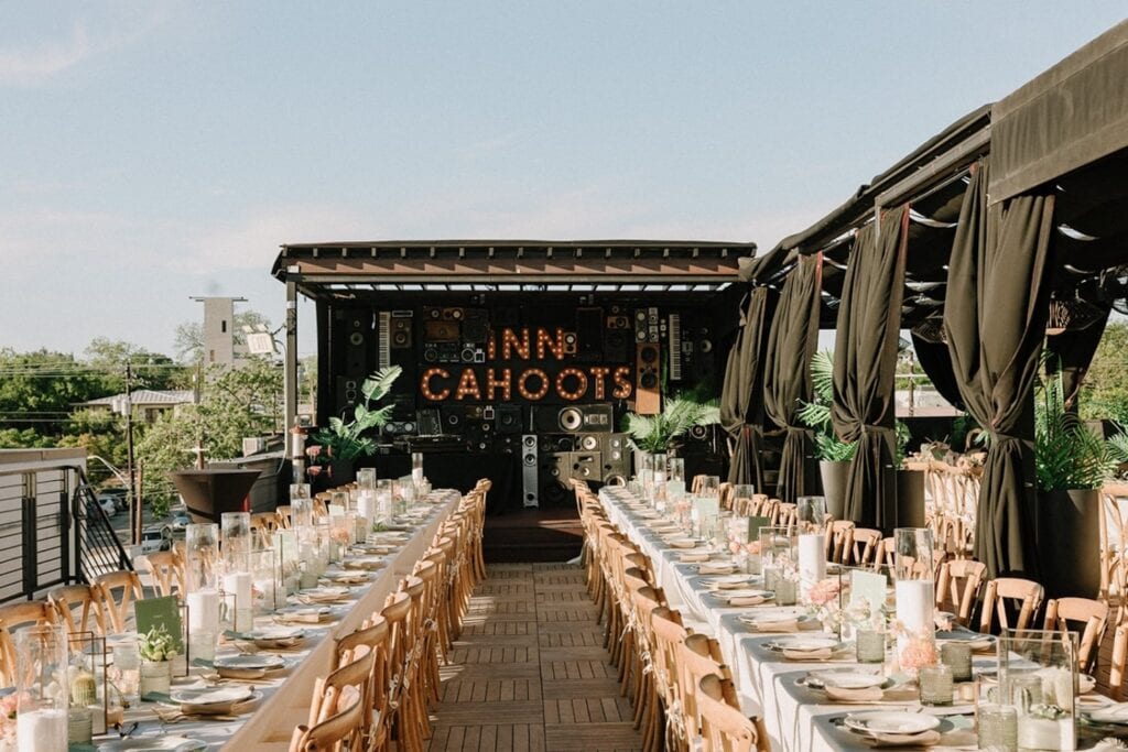 Long reception tables are set up with candles and small centerpieces on a rooftop