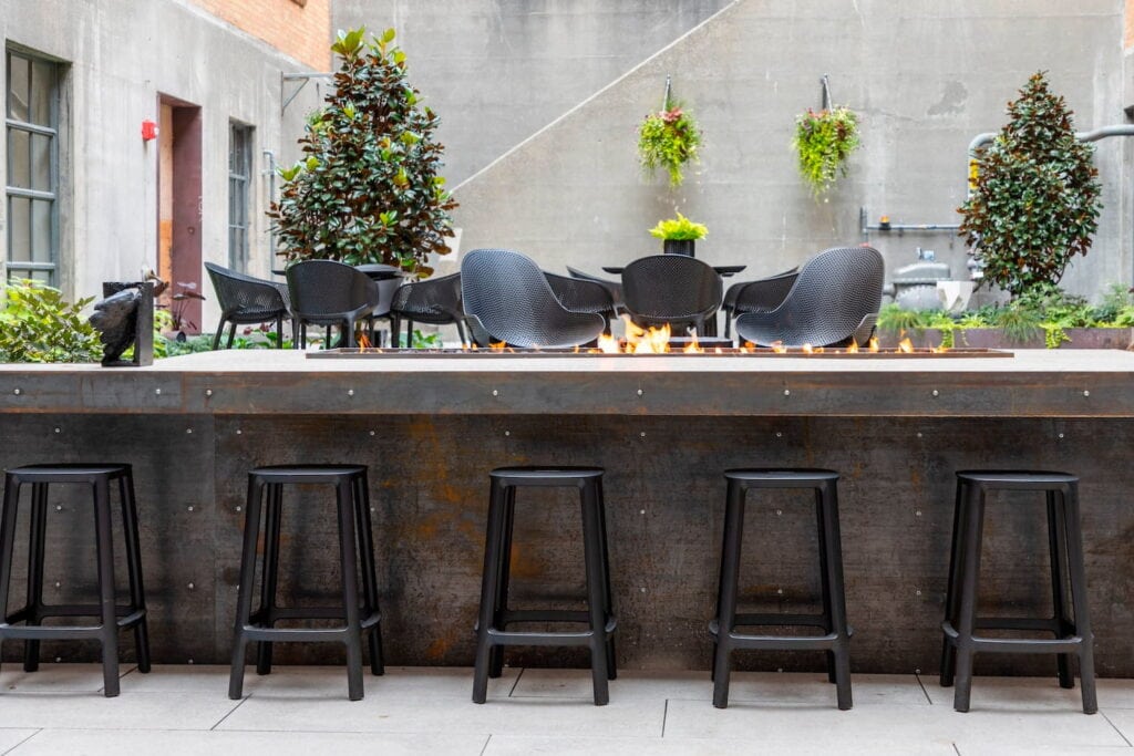 Outdoor bar space with a sunken seating area, fire pit and multiple tables and chairs
