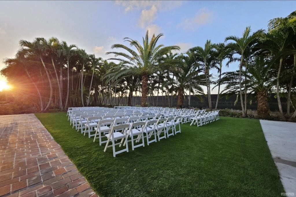 The sun sets beyond palm trees, which are the backdrop for a very simple outdoor wedding ceremony venue