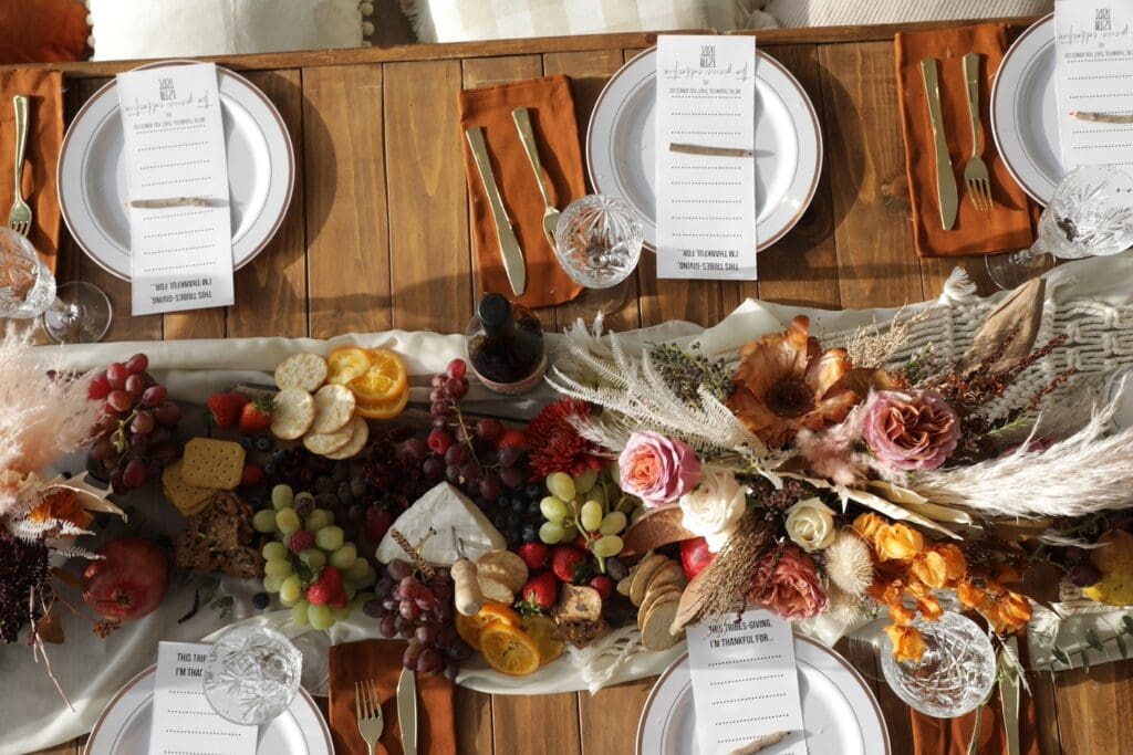 Overhead shot of a dining table set with a runner filled with fruit and cheese