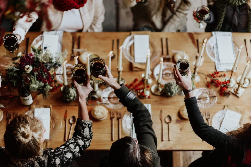 An overhead shot of a dining table where guests toast with wine glasses