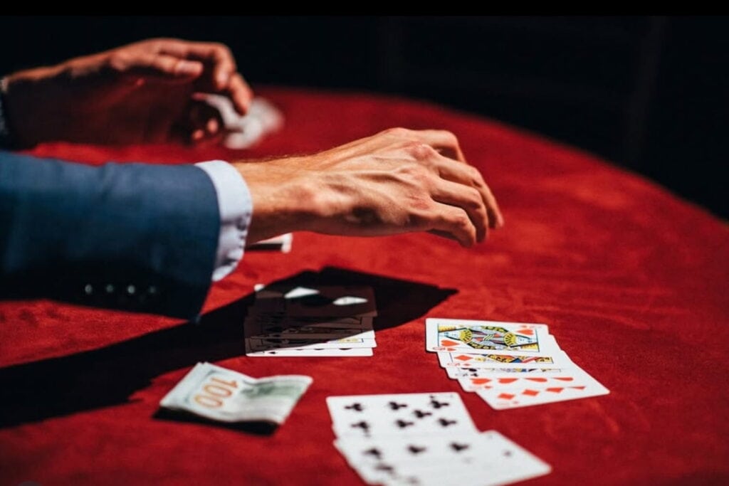 Closeup of a hand dealing a deck of cards on a red velvet table