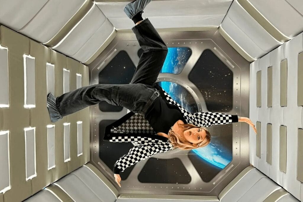 A woman in a black and white check jacket enjoys a zero gravity installment