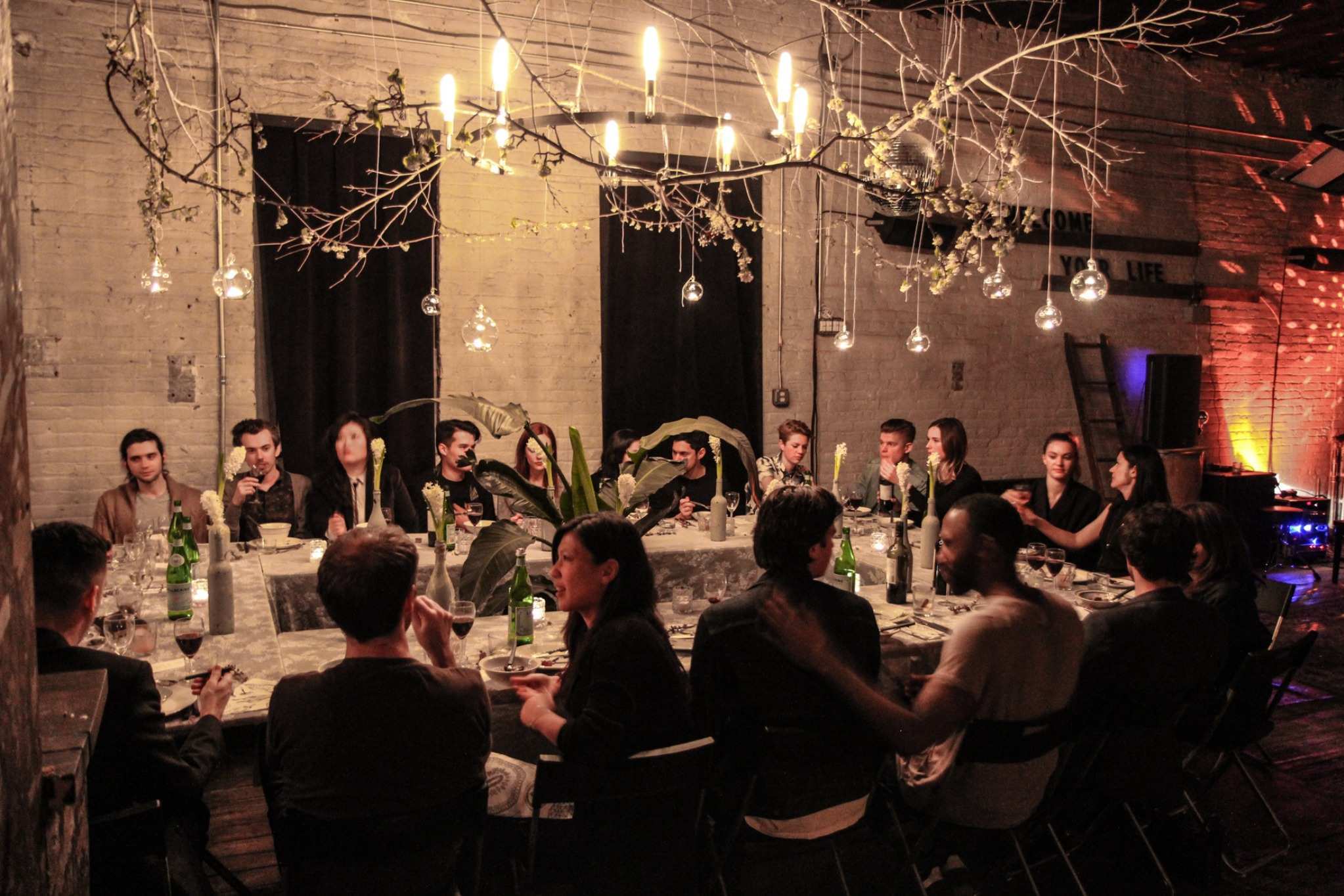 Curated Brooklyn dinner party in exposed-brick venue with dramatic lighting
