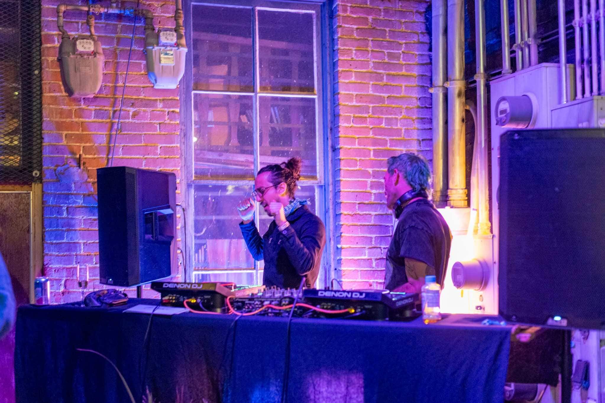 DJs performing at a Denver venue with purple neon lighting