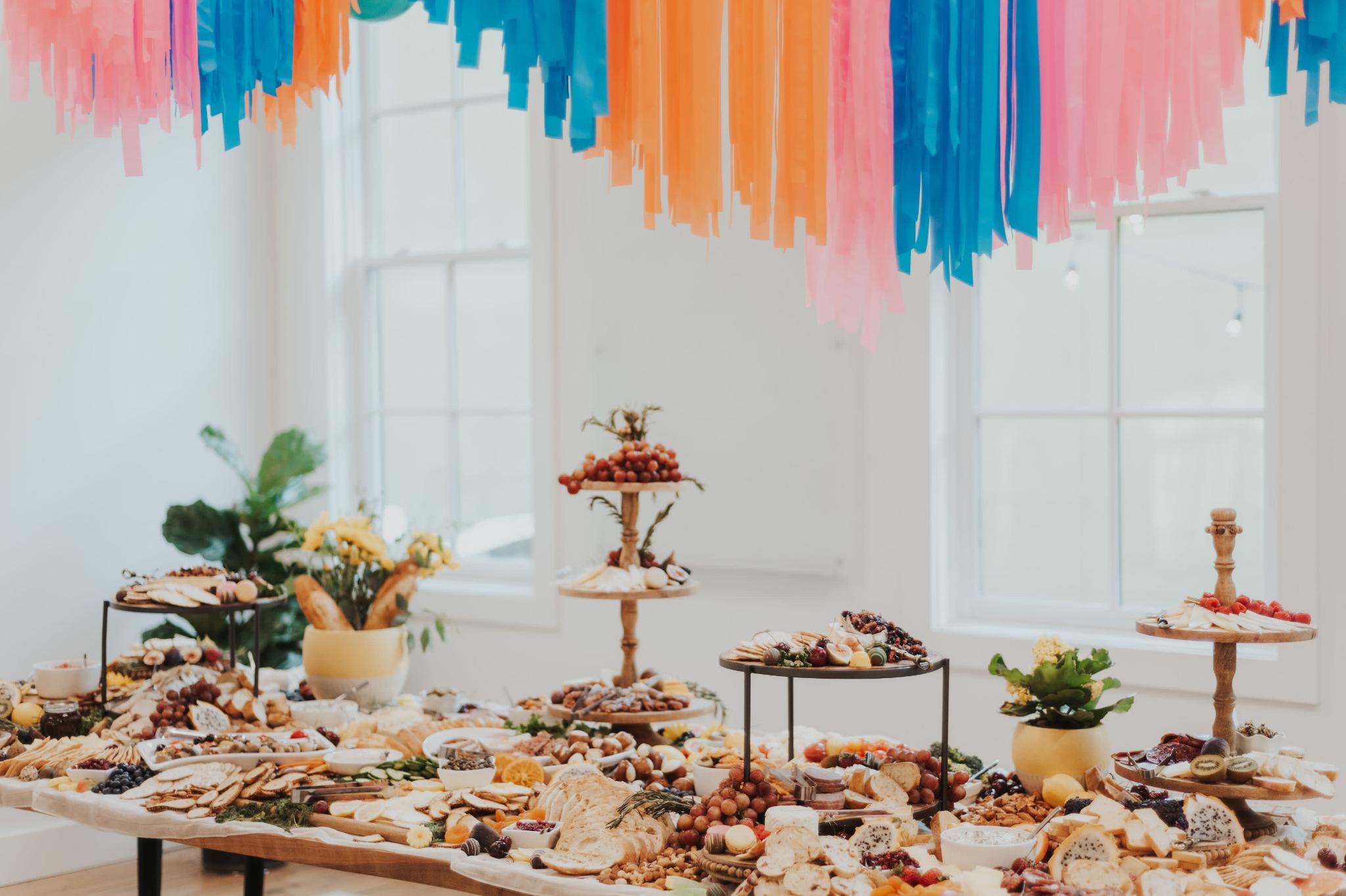 Colorful grazing table with charcuterie and hanging ribbon décor for parties
