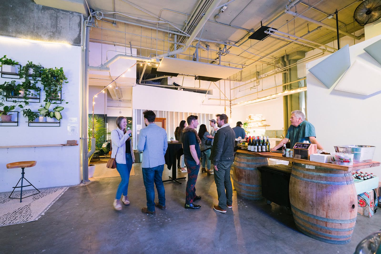 Guests mingling at an industrial-style Milwaukee venue with barrel bar