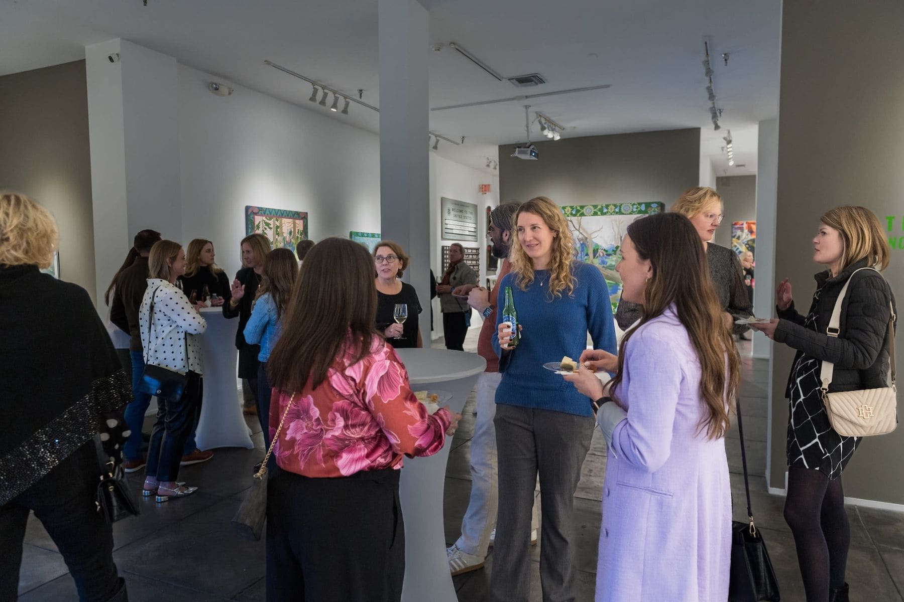 Guests mingling at a New Orleans gallery-style event with colorful artwork