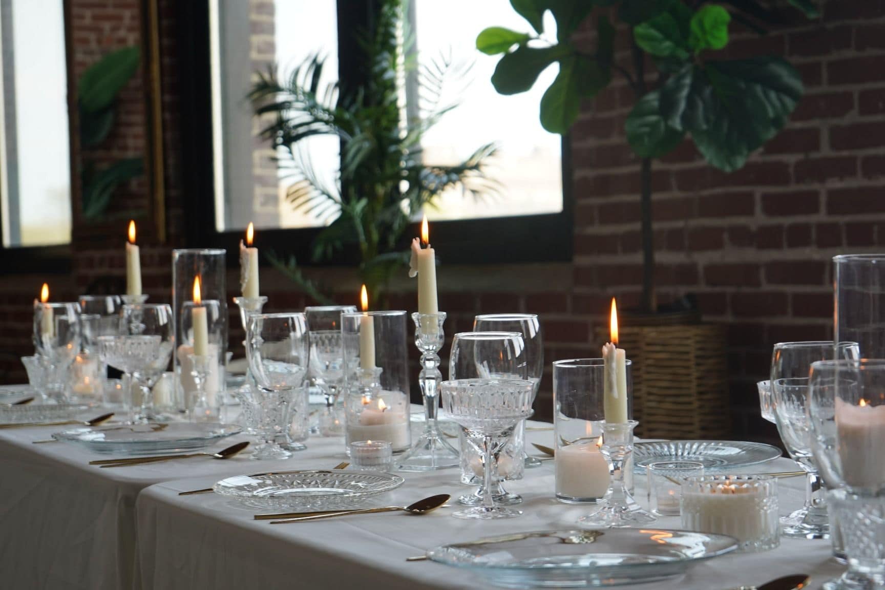 Elegant Philadelphia event tablescape with candles, greenery, and brick-wall ambiance