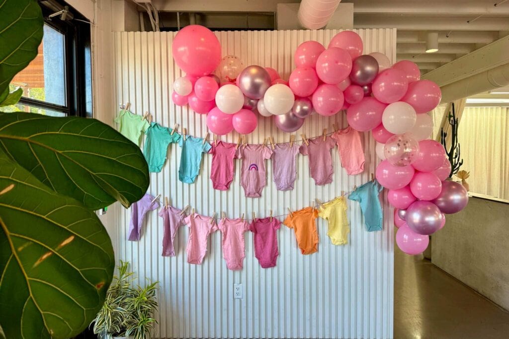 Baby shower with rainbow onesies and balloons set up by party planner in San Antonio