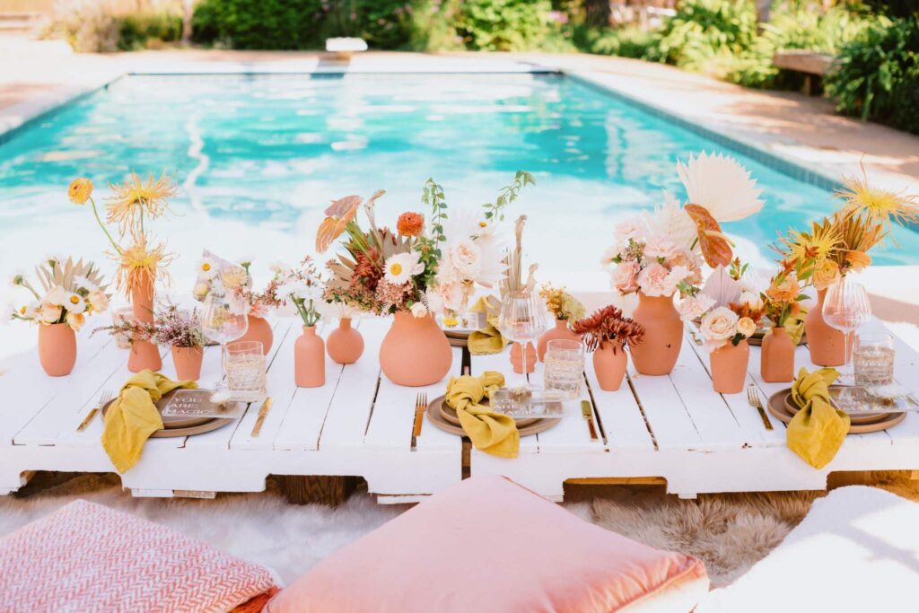Poolside San Diego party setup with flowers in vases
