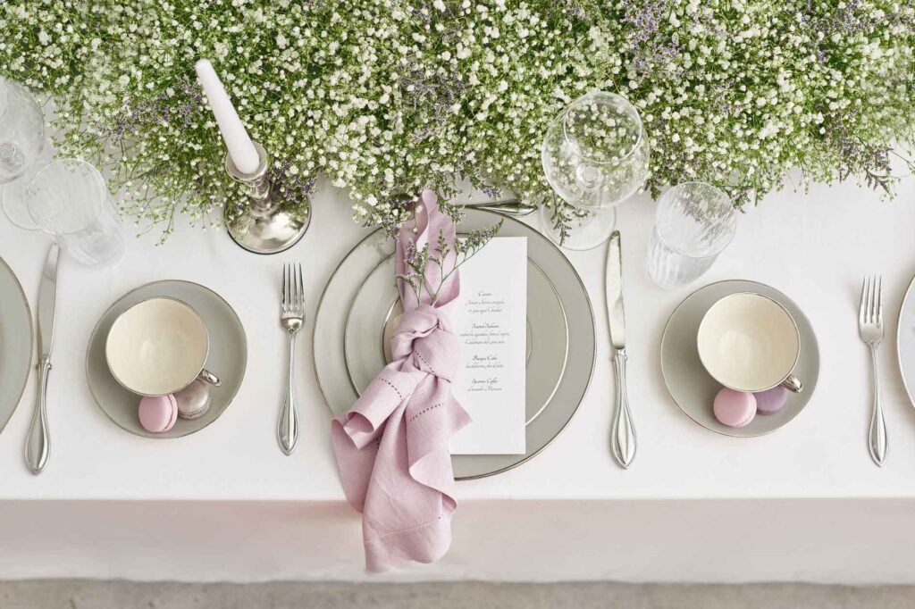 Table setting with greenery, candles, and pink napkin designed by Tampa party planner