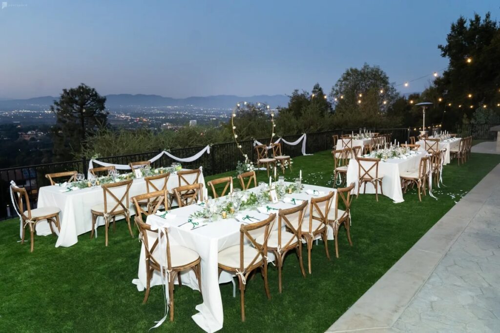 Outdoor wedding reception on a budget venue with tables with white linens and wood chairs