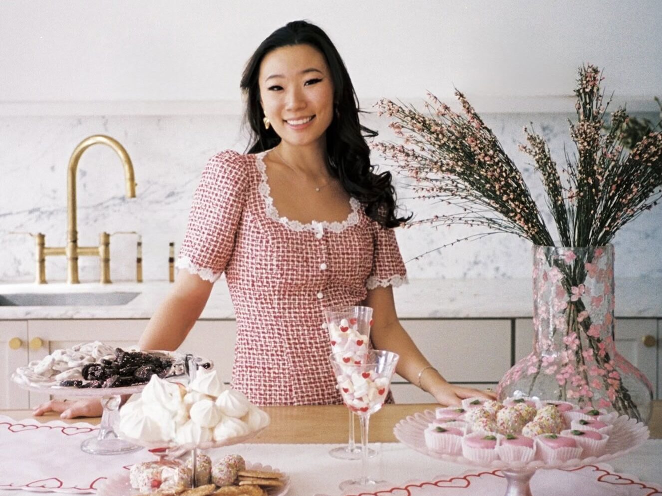 Woman in kitchen with Galentines food ideas and sweets on table