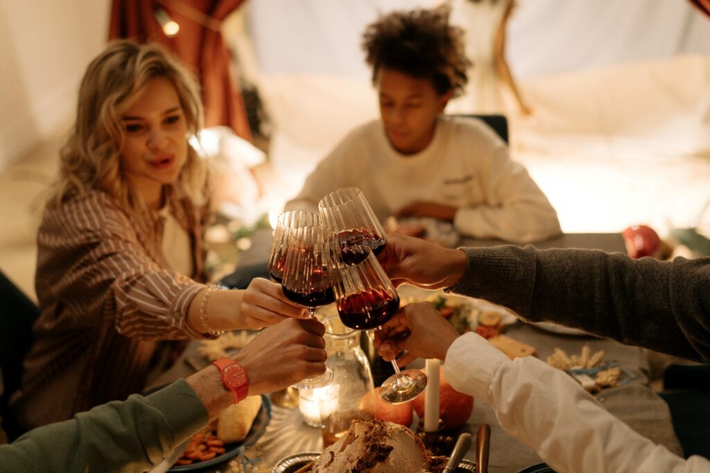 people making a toast at table with wine