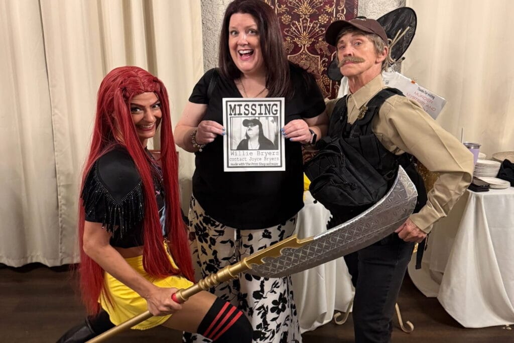 Three people pose for the camera in costume at a murder mystery dinner