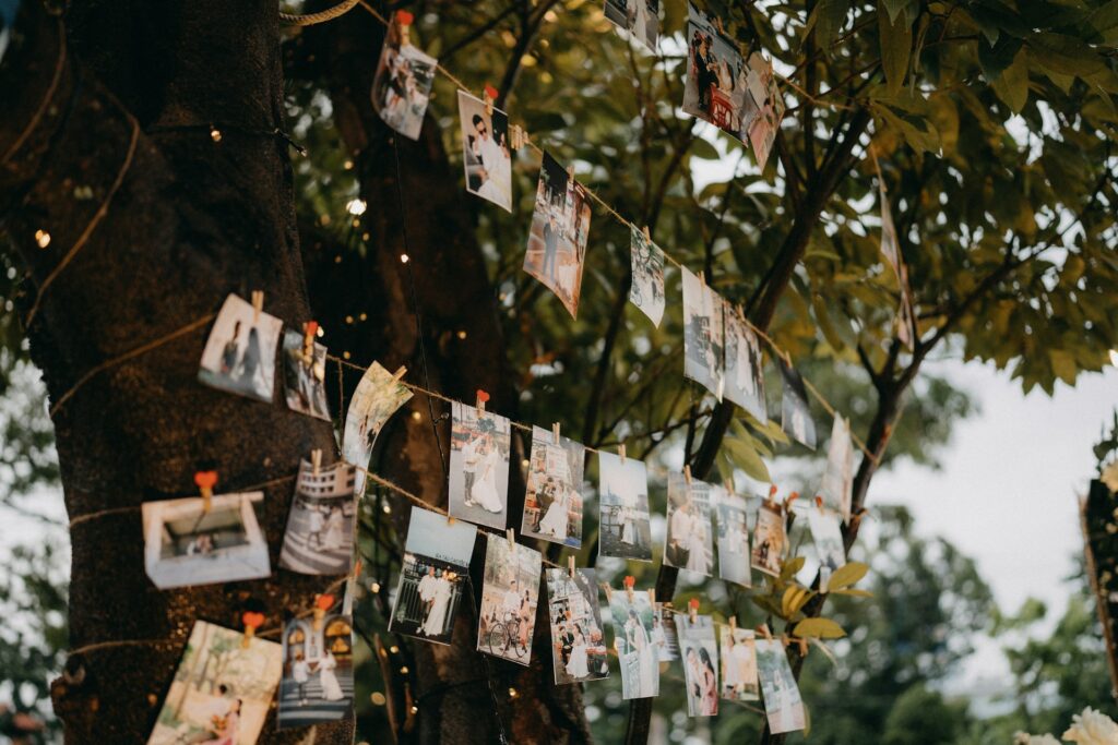 Printed photos hung up with clothes pins on twine outdoors at reception