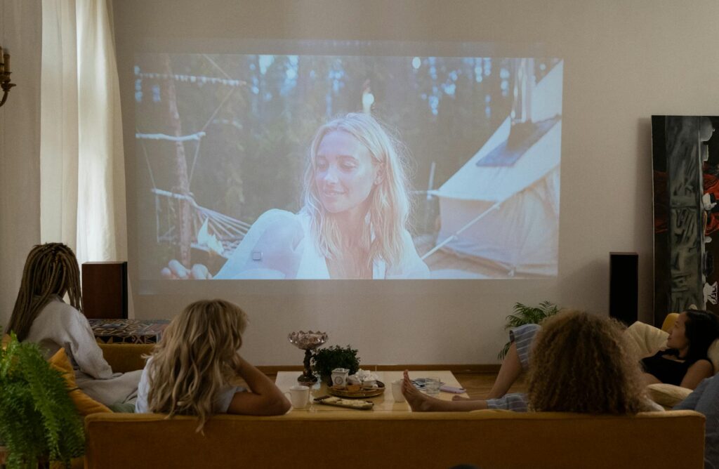 Four friends sitting on couch watching movie on projector for rom com Galentines theme