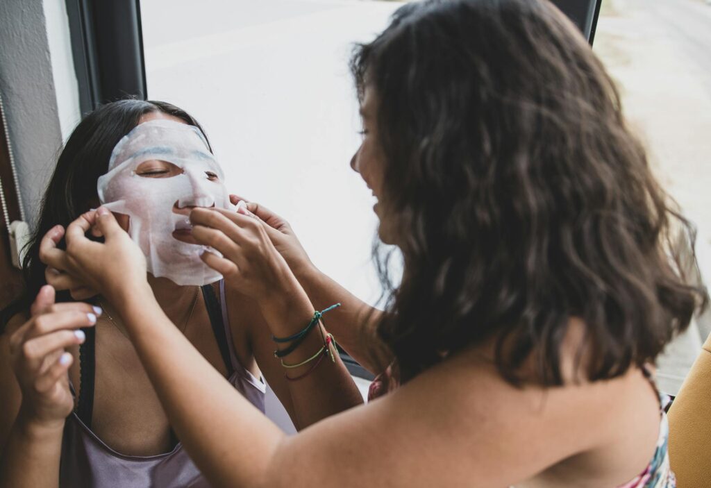 Friend putting sheet mask on other friend for self care Galentines idea