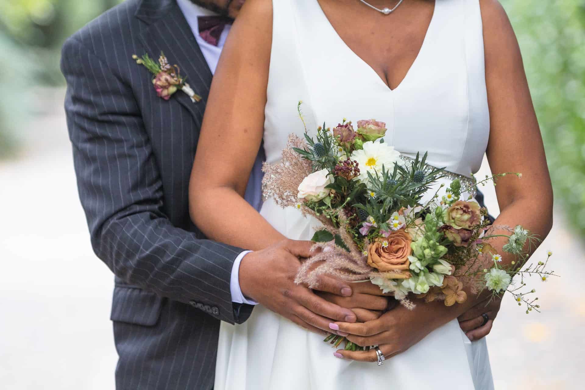 groom hugging bride holding a bouquet