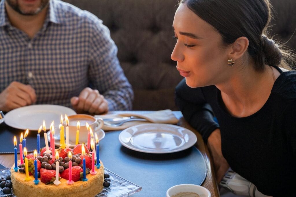 22nd birthday party with woman blowing out candles on cake in restaurant