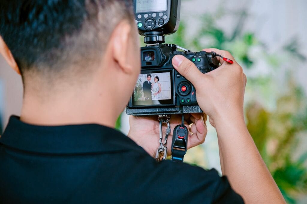 Over the shoulder of a photographer taking pictures of a couple at their wedding reception on a budget