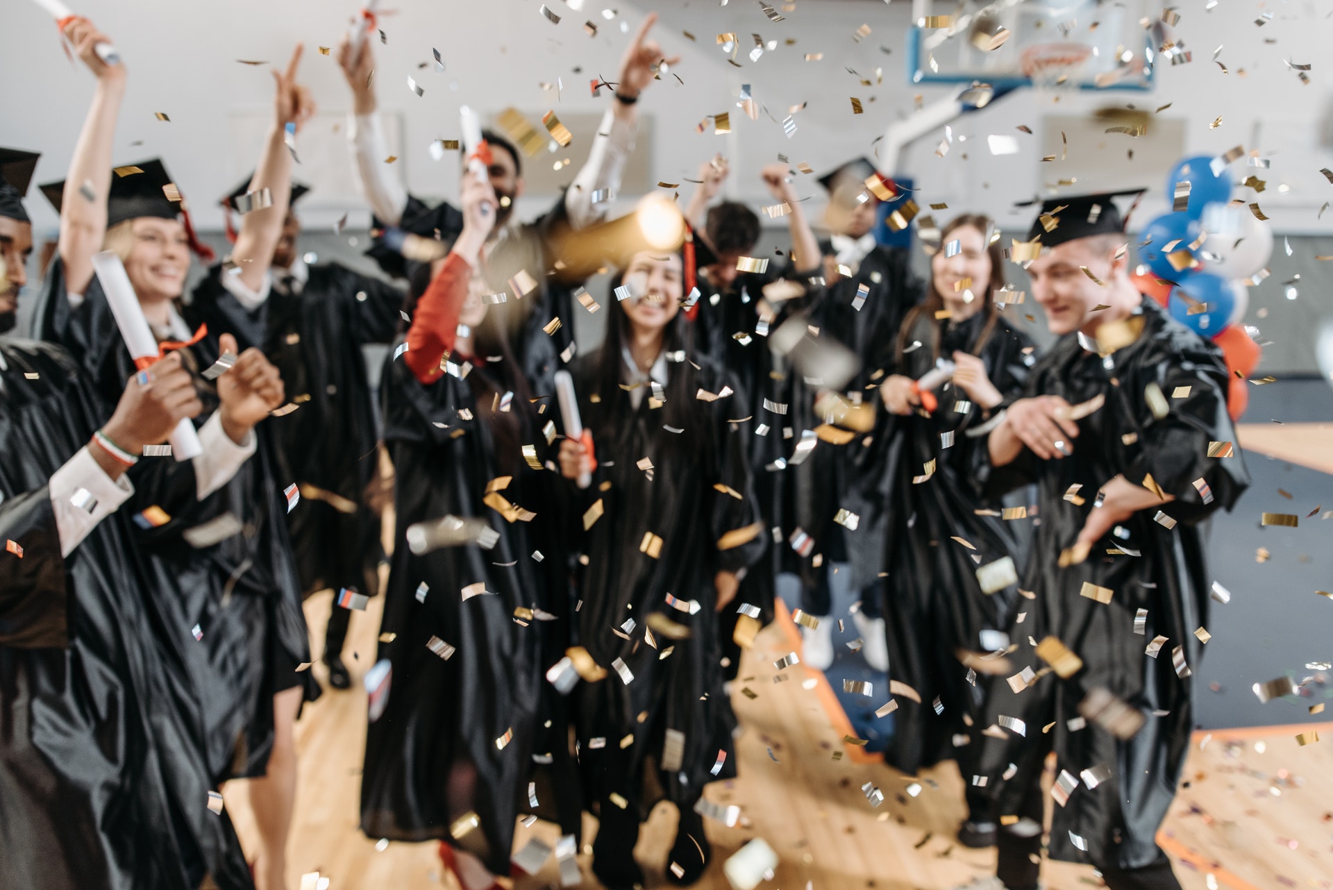 graduates dancing in gym with gold confetti