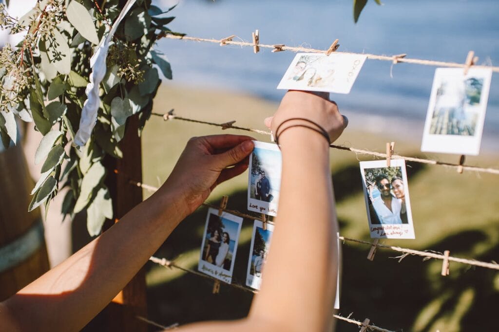 Budget wedding reception activity of person hanging polaroid photo on twine