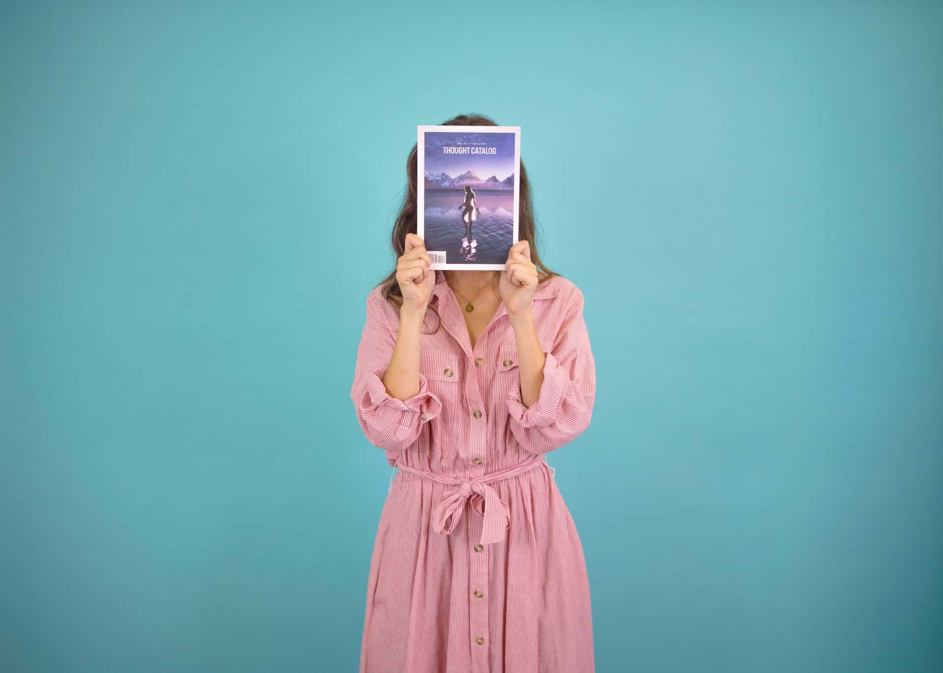 woman holding magazine over face