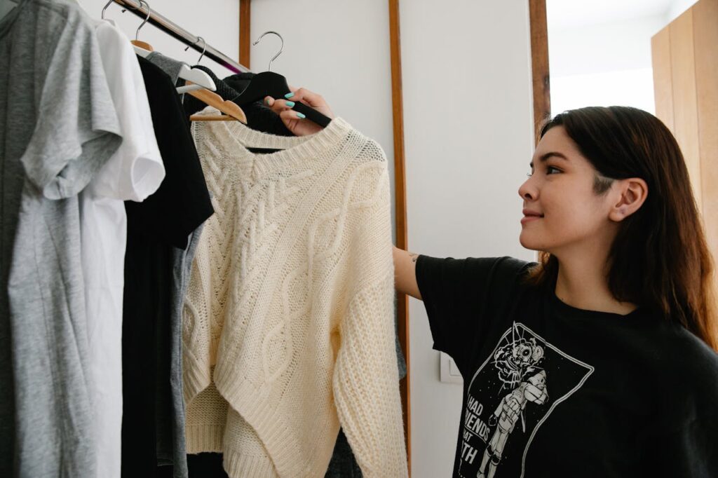 Woman taking a cream sweater off the clothing rack for a Friendsgiving outfit